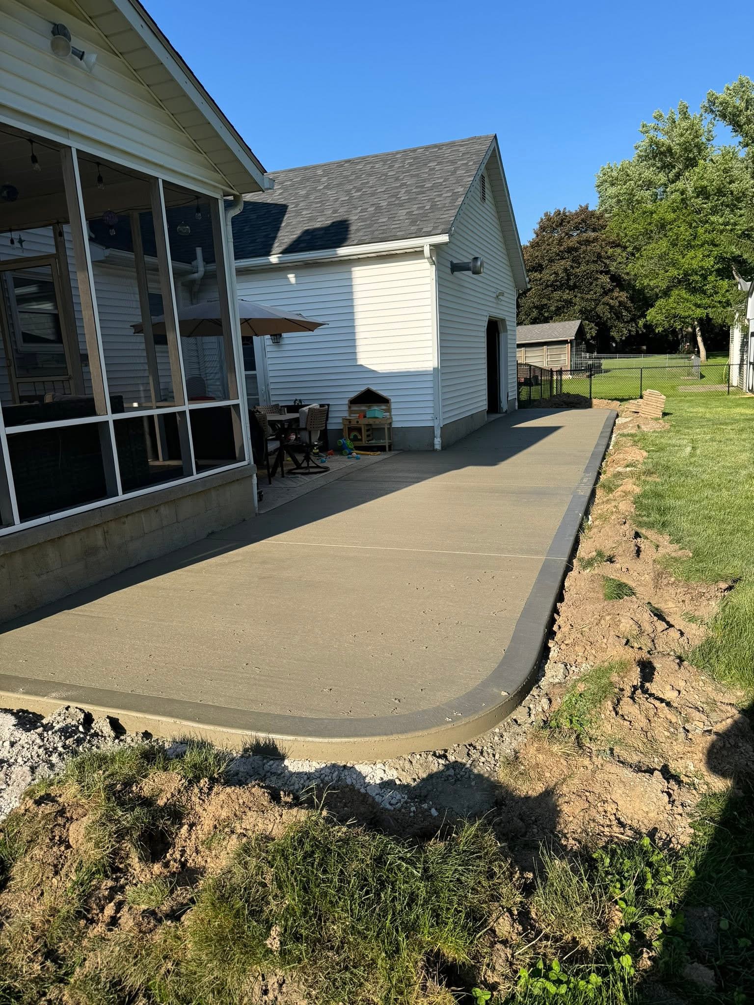 Large finished broom-finished concrete patio beside a Northeast Ohio home
