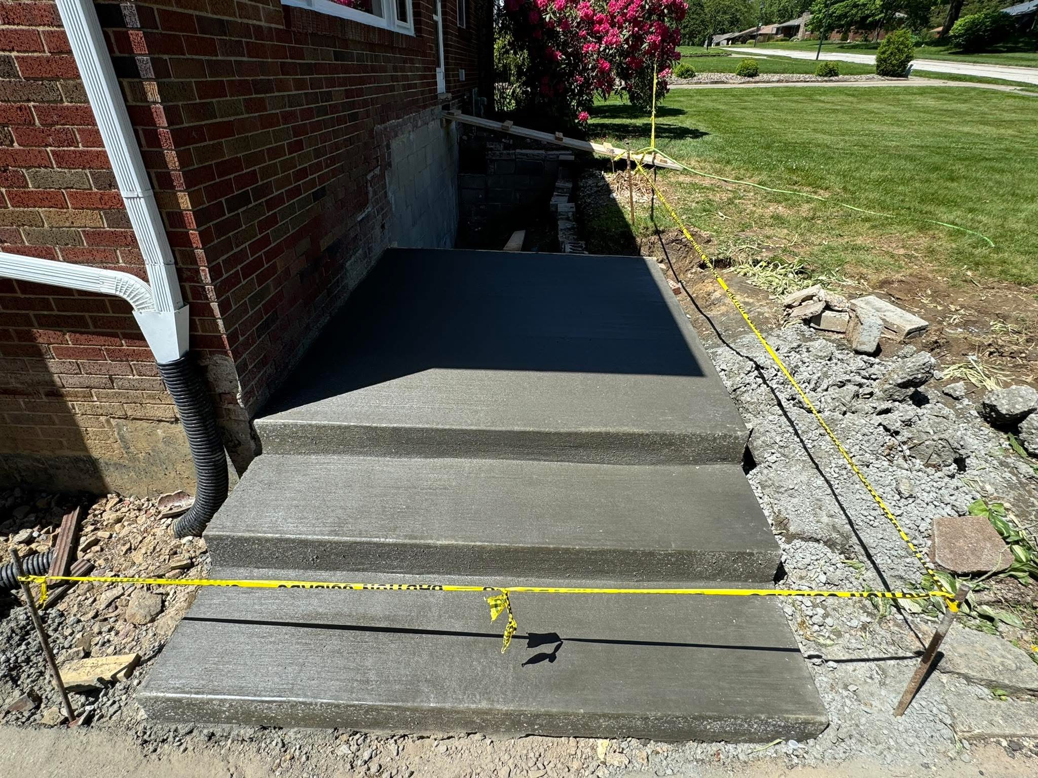 Newly poured concrete steps and landing against a brick home near Akron Ohio